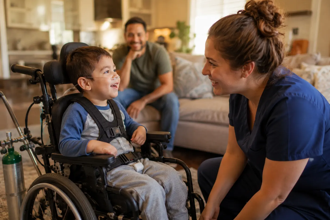 A boy with a tracheostomy points at his ventilator, smiling, while a nurse in navy scrubs and his father look on.